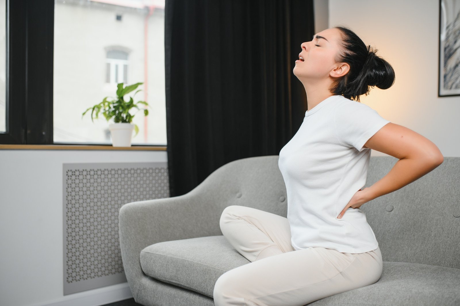 Sad young woman touching back feeling backache morning discomfort low lumbar muscular kidney pain