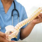 Asian doctor holding spinal nerve and bone model, Lumbar spine displaced herniated disc fragment